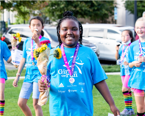 A Girls on the Run participant smiles while crossing the finish line! 